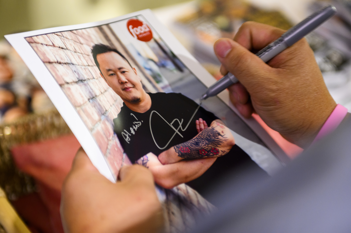 chef tila signing a photograph of himself
