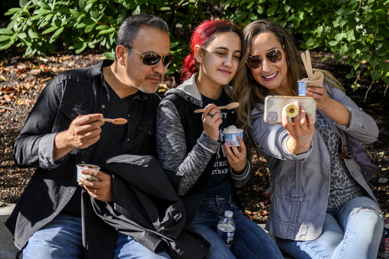 Three people are taking a picture together while they eat ice cream at Northeastern's Family and Friends Weekend.