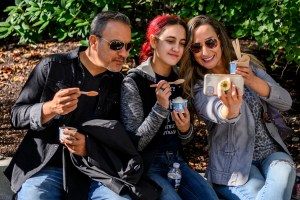 Three people are sitting together while eating ice cream during Northeastern's Friends & Family Weekend.