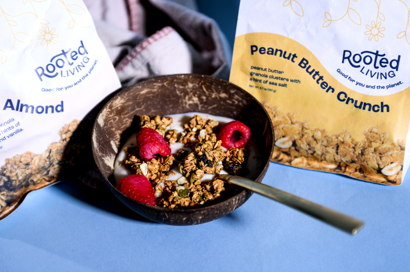 bowl of granola next to packages of rooted living granola