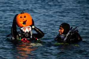 scuba diver holding a jack-o-lantern above their head