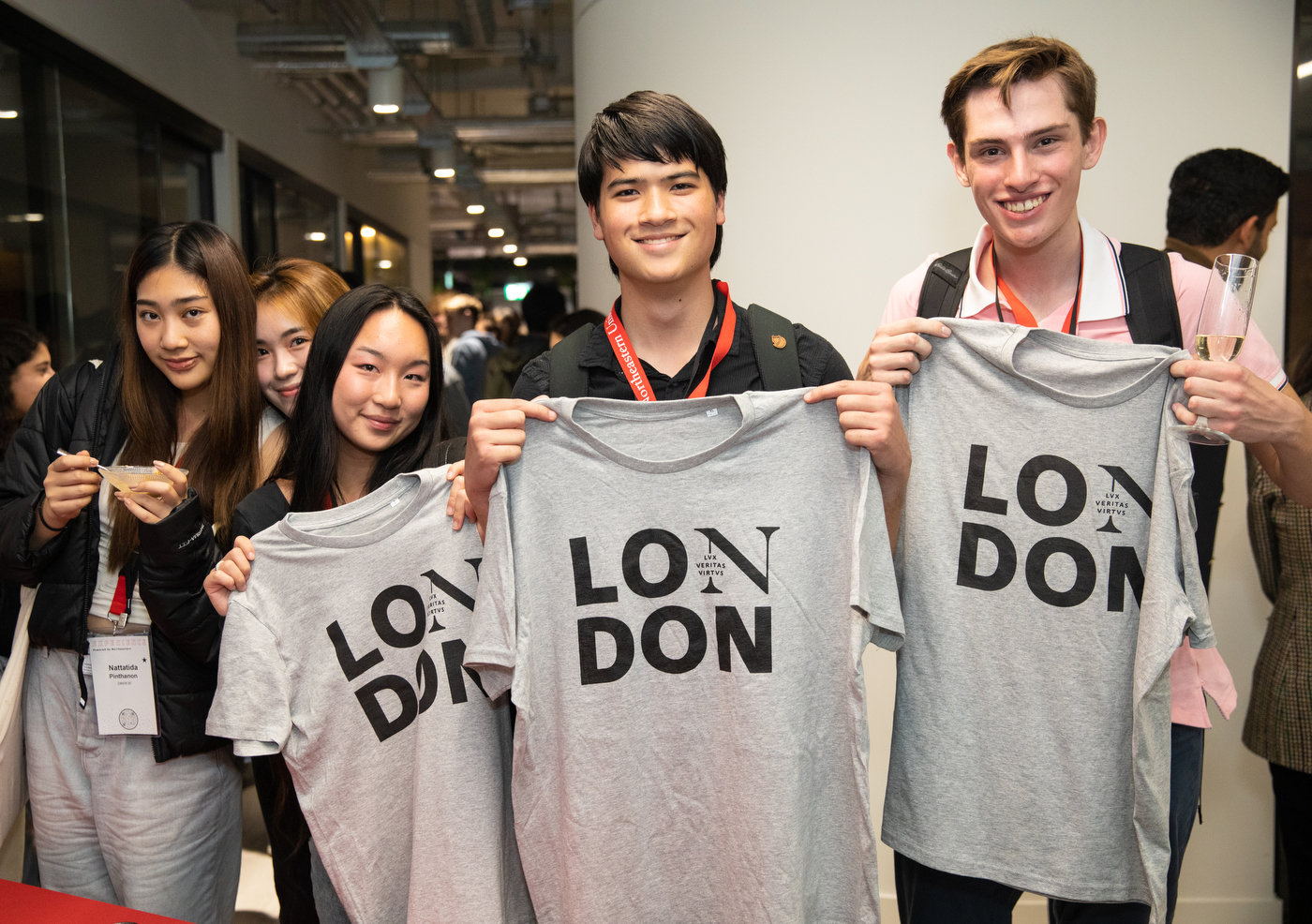 three people hold up t-shirts that say London on them