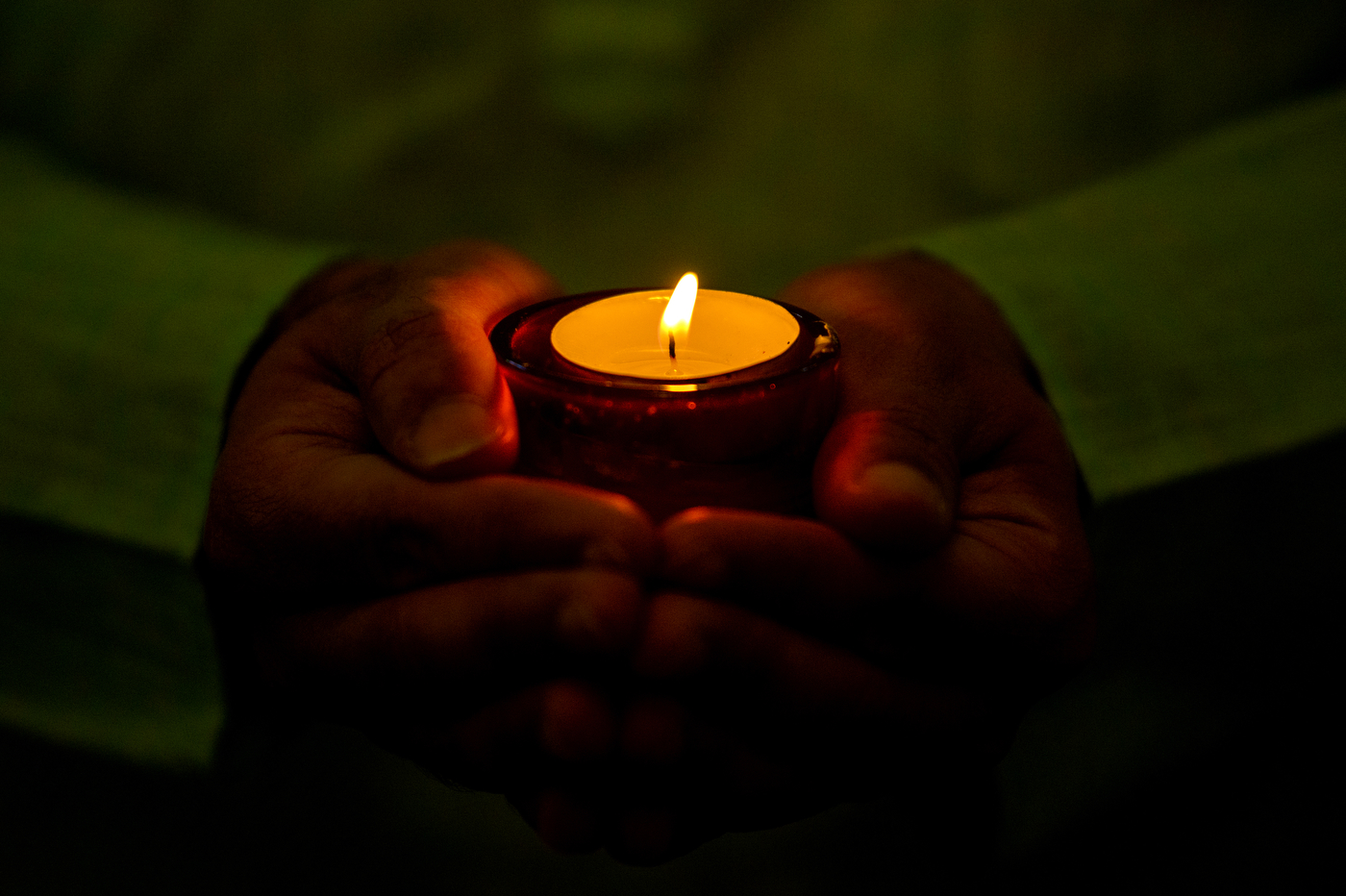 Hands holding a lit candle