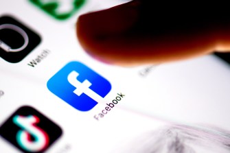 Finger hovering over Facebook app on iPhone