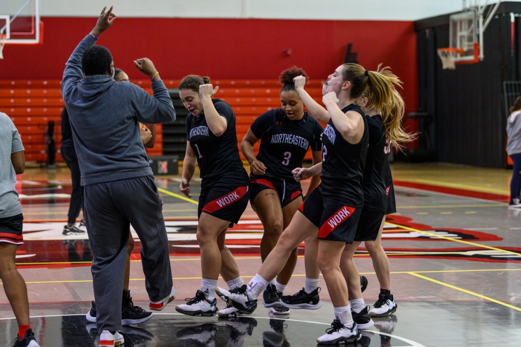 Members of the Northeastern women’s basketball team dance and sing at midcourt during practice in the Cabot Center.