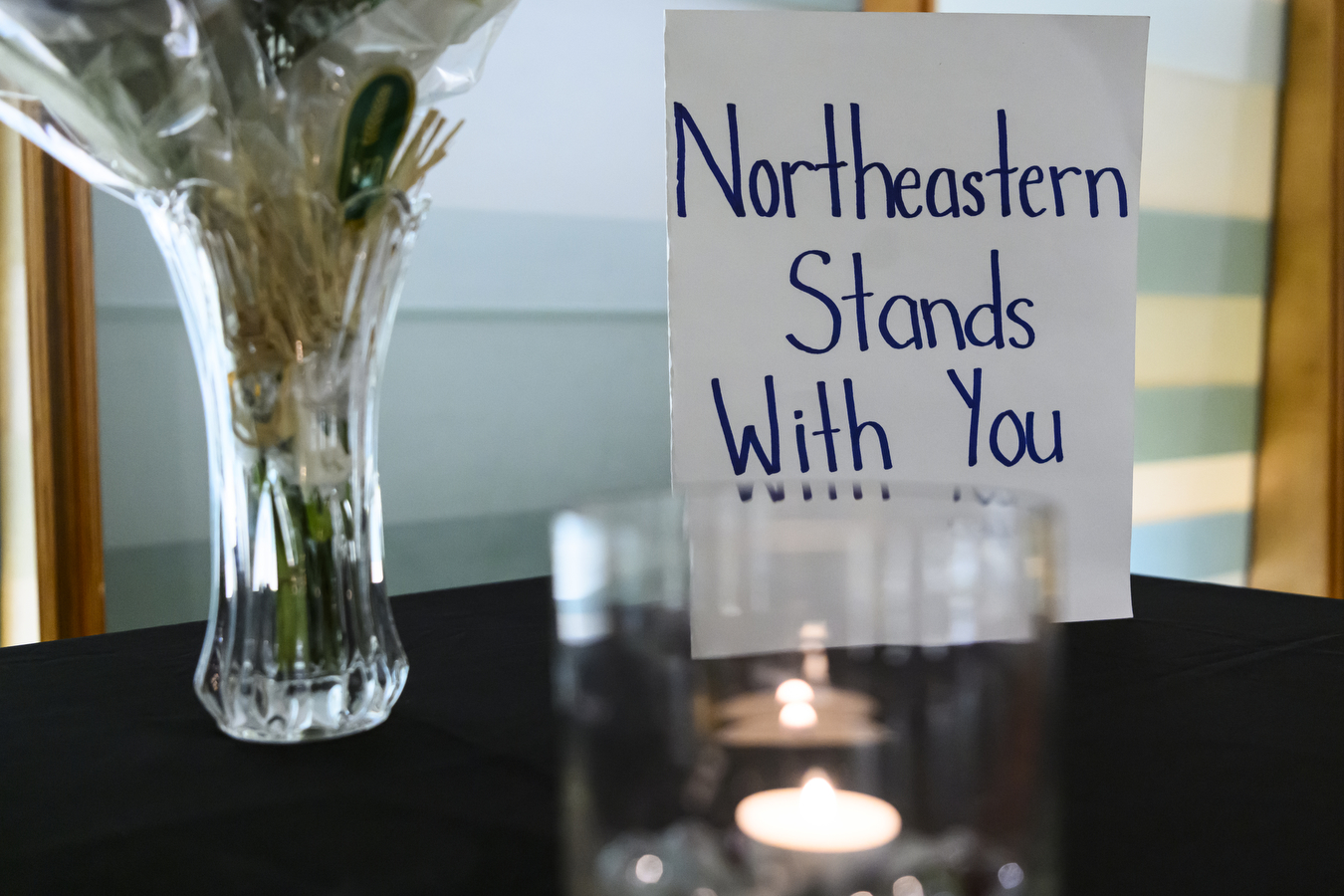 Sign that reads 'Northeastern Stands With You' behind a lit candle