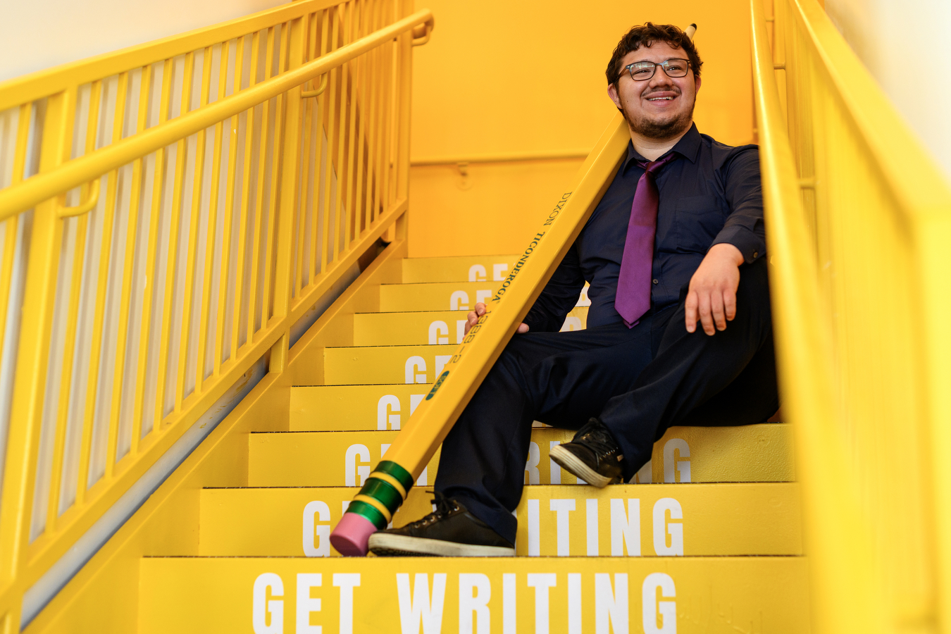 victor mendevil sitting on yellow stairs that say 'get writing' on them