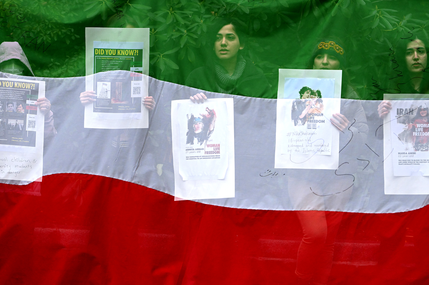overlay of iranian flag over photo of students holding protest signs