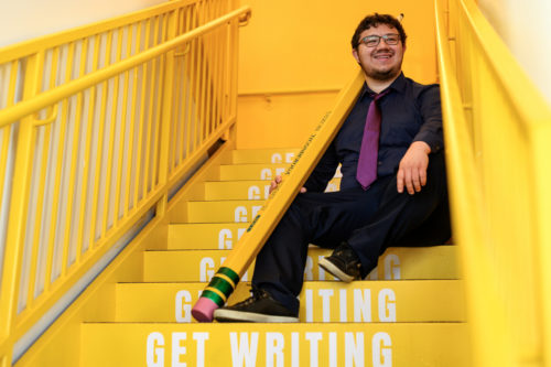 victor mendevil sitting on yellow stairs that say 'get writing' on them