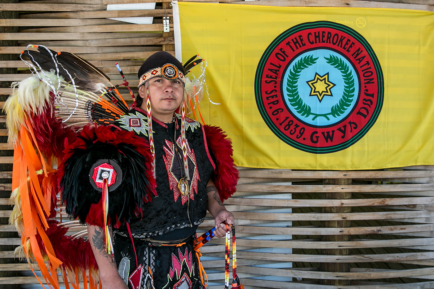 native american posing next to cherokee flag