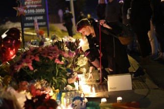 person leaning over candlelit memorial in colorado springs