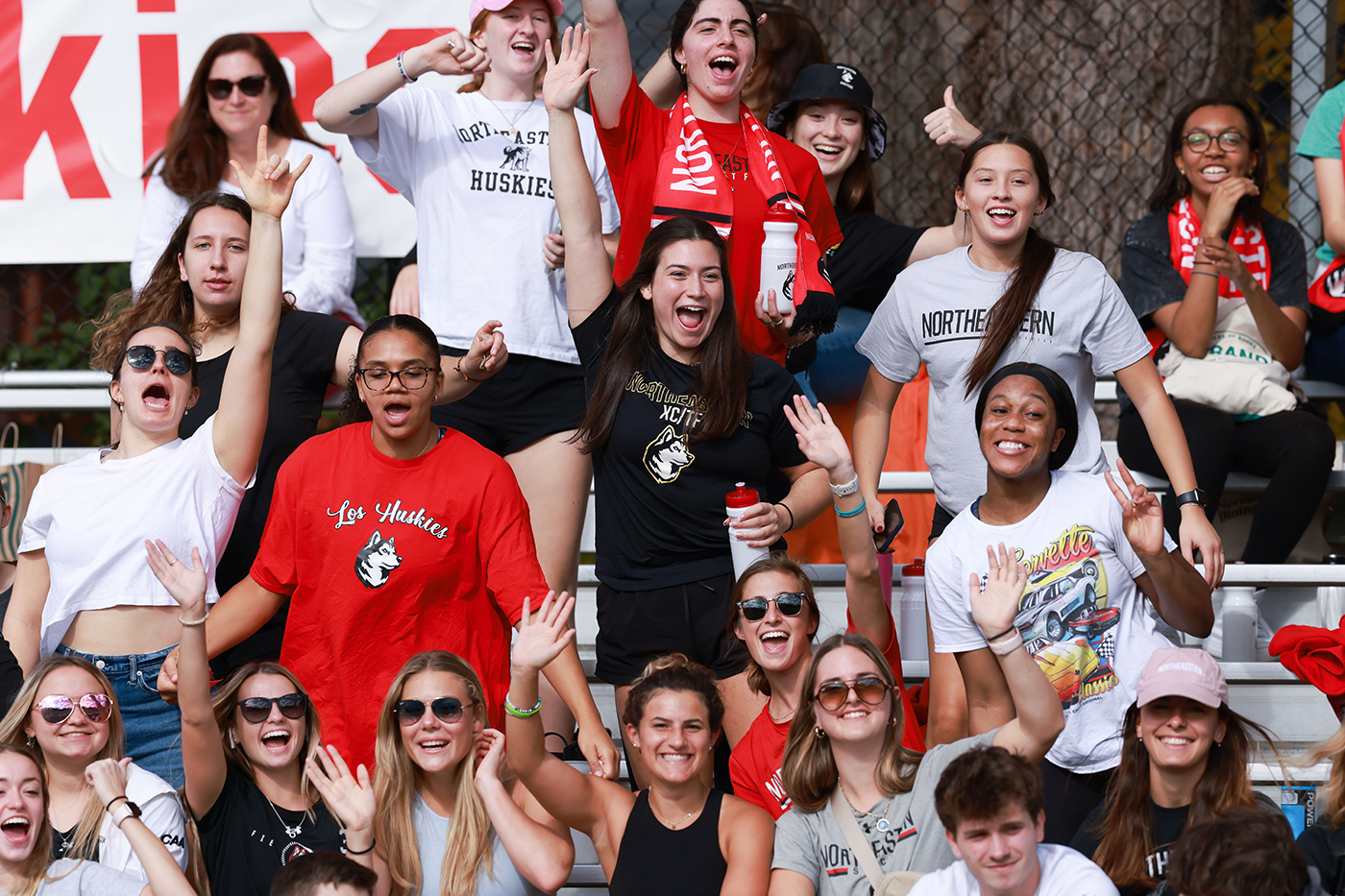 A crowd of people is cheering on the Northeastern women's soccer team.