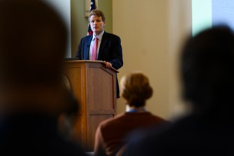 Former U.S. Rep. Joseph P. Kennedy III standing at a podium in front of a large crowd.