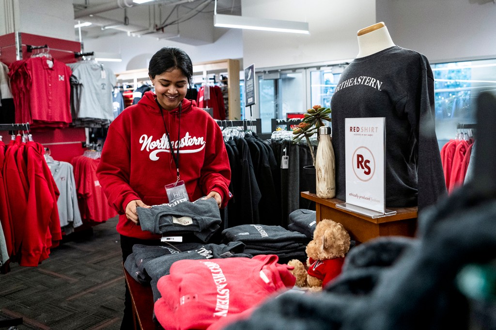 Smiling bookstore employee folds a sweatshirt