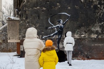 people looking at banksy mural