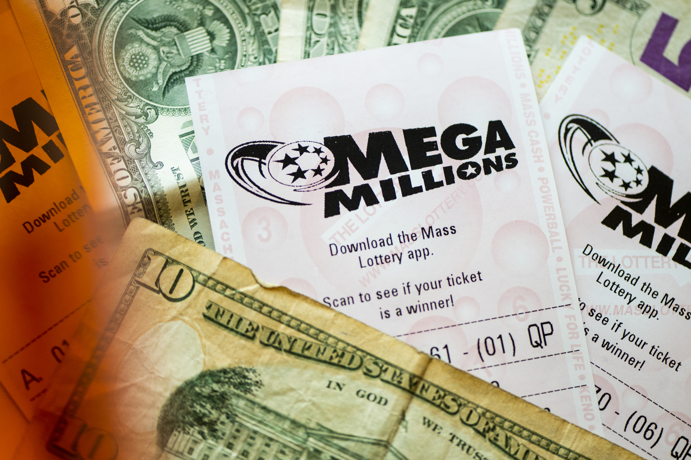 mega millions lottery ticket half covered by a US ten dollar bill