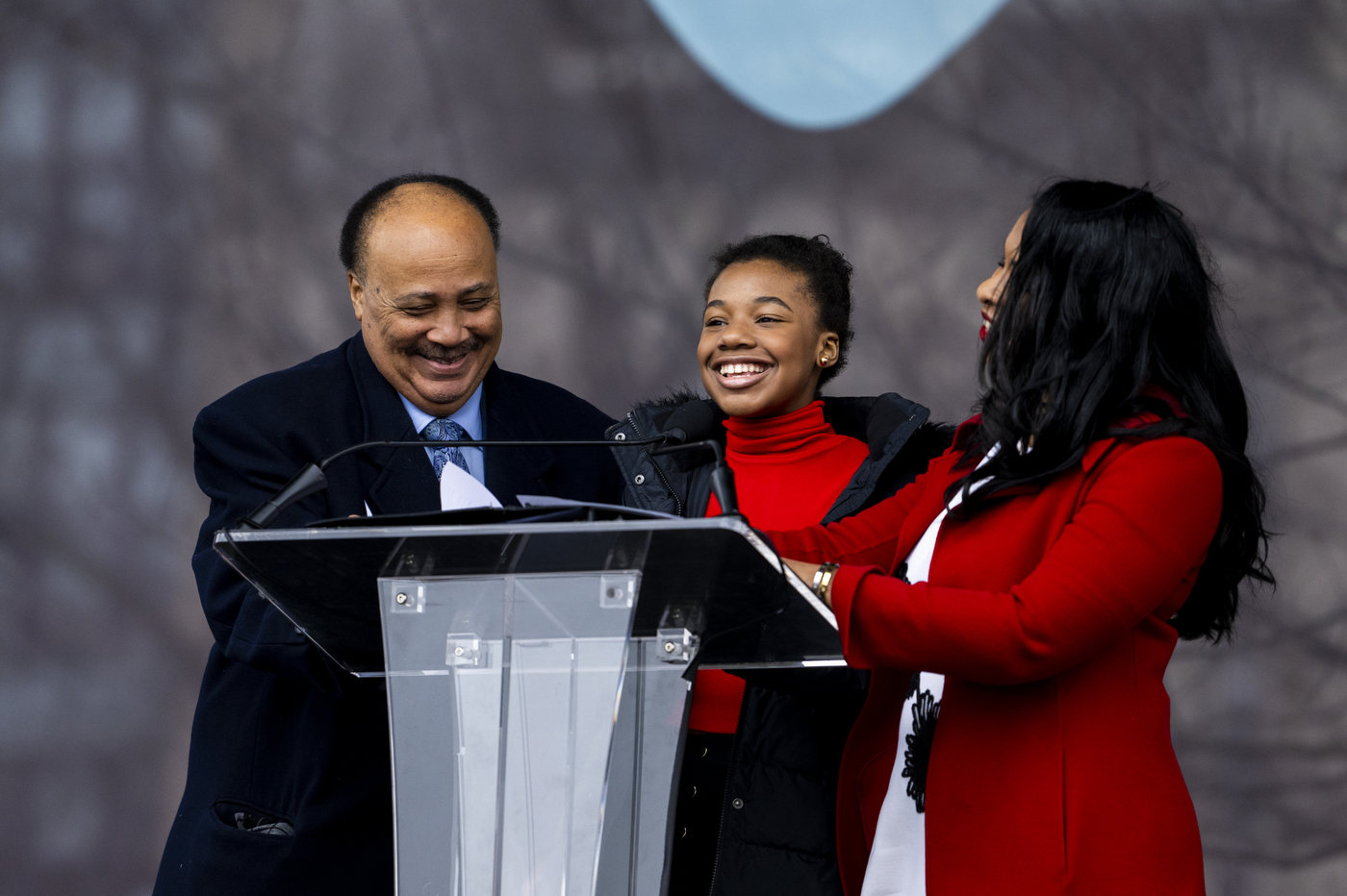 three people smile as they stand behind a podium