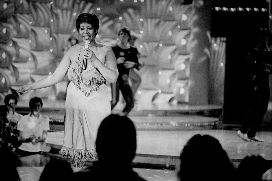 Aretha Franklin singing on stage in front of a crowd
