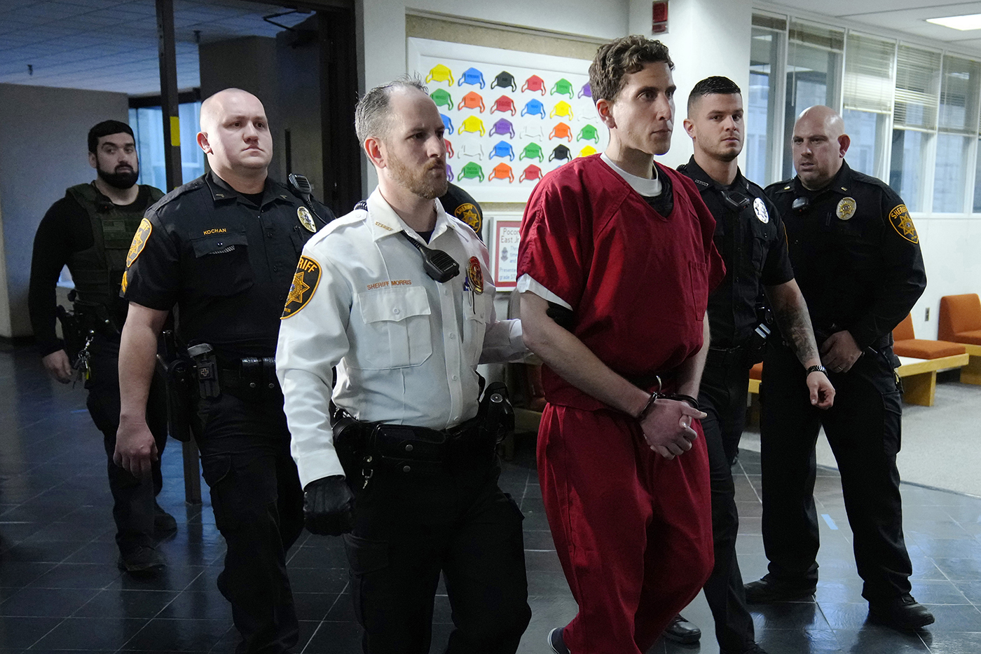 bryan kohberger being escorted from an extradition hearing by police officers