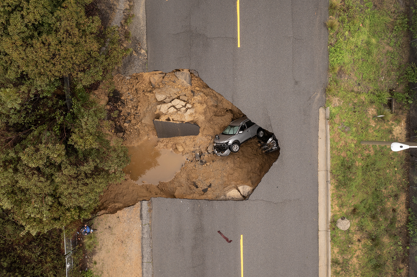 In an aerial view, a car and a pickup truck are seen inside a sinkhole.