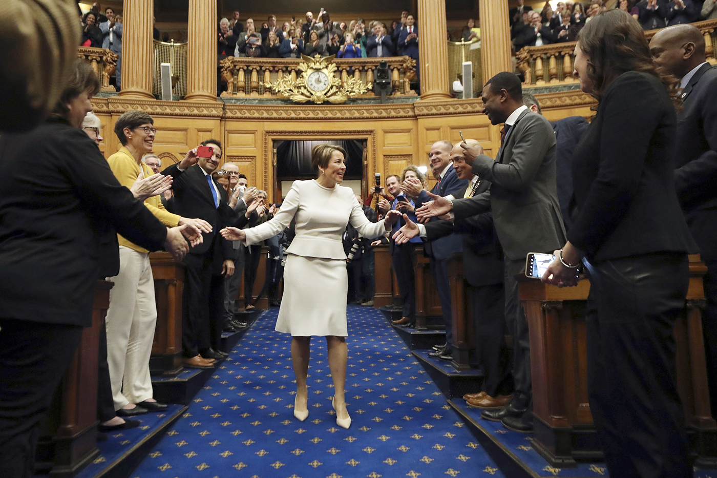 maura healey shaking hands as she walks down the aisle of the house of chambers