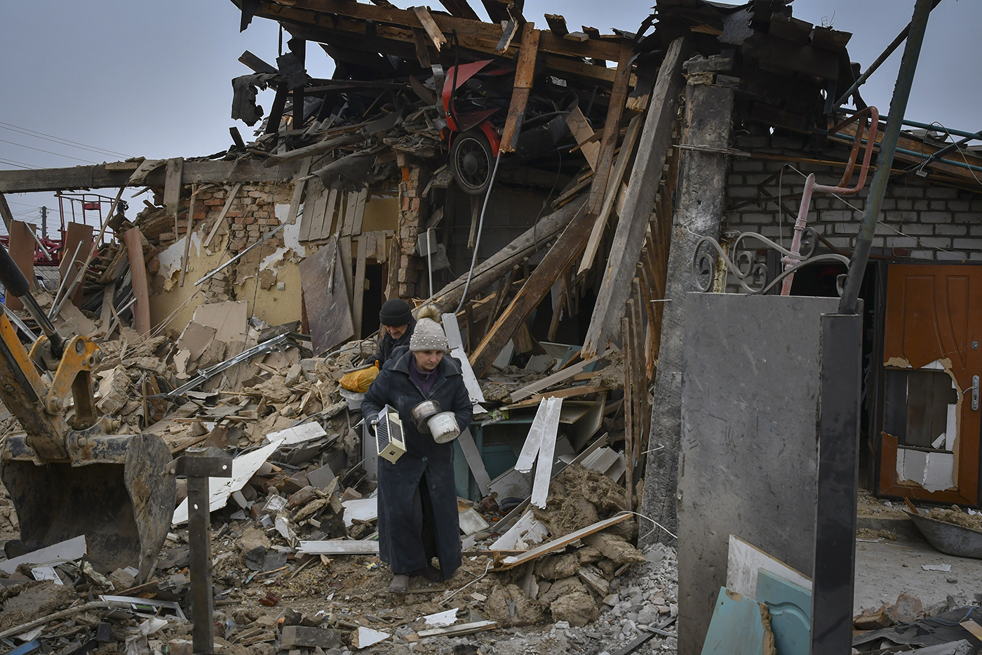 person carrying belongings out of a bombed home