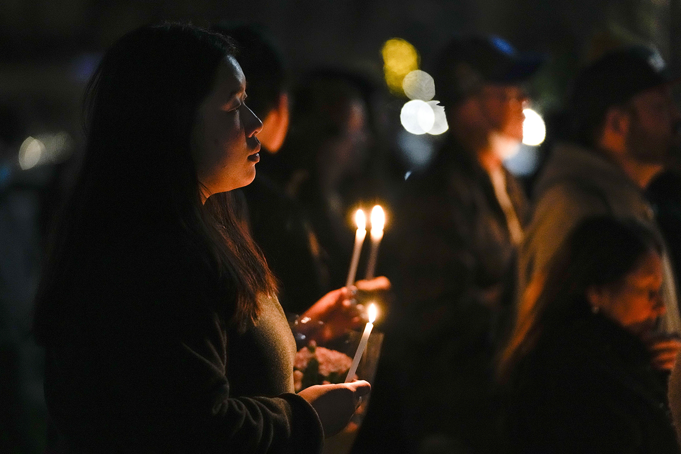People gathered outside holding candles in the dark