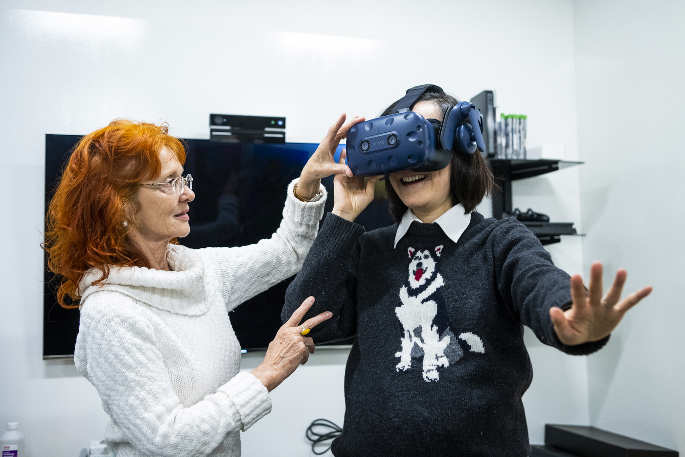 Two professors play an interactive video game with a VR headset
