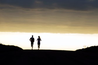 silhouette of two people running side by side