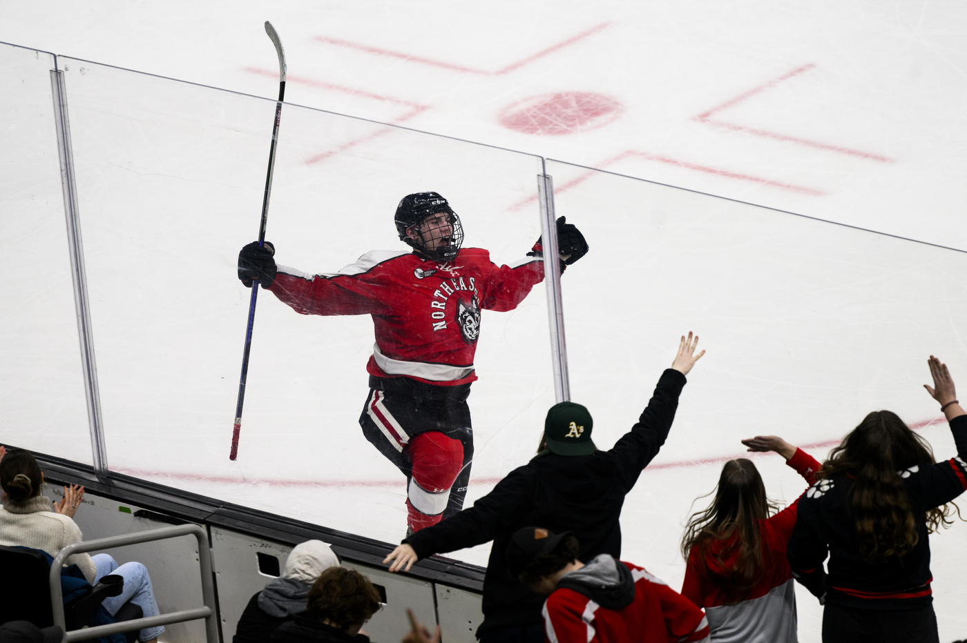 northeastern hockey player skating with arms up in celebration