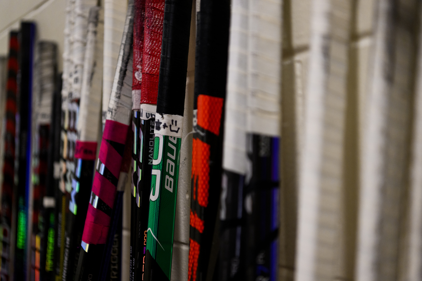row of hockey sticks leaned up against a wall