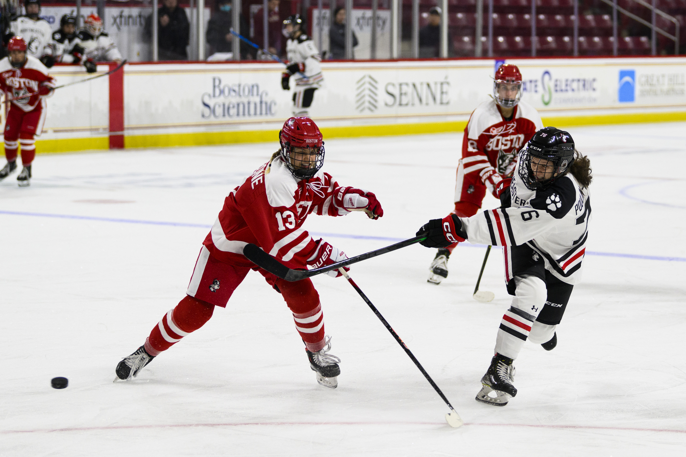 northeastern and BU womens hockey players battling for the puck