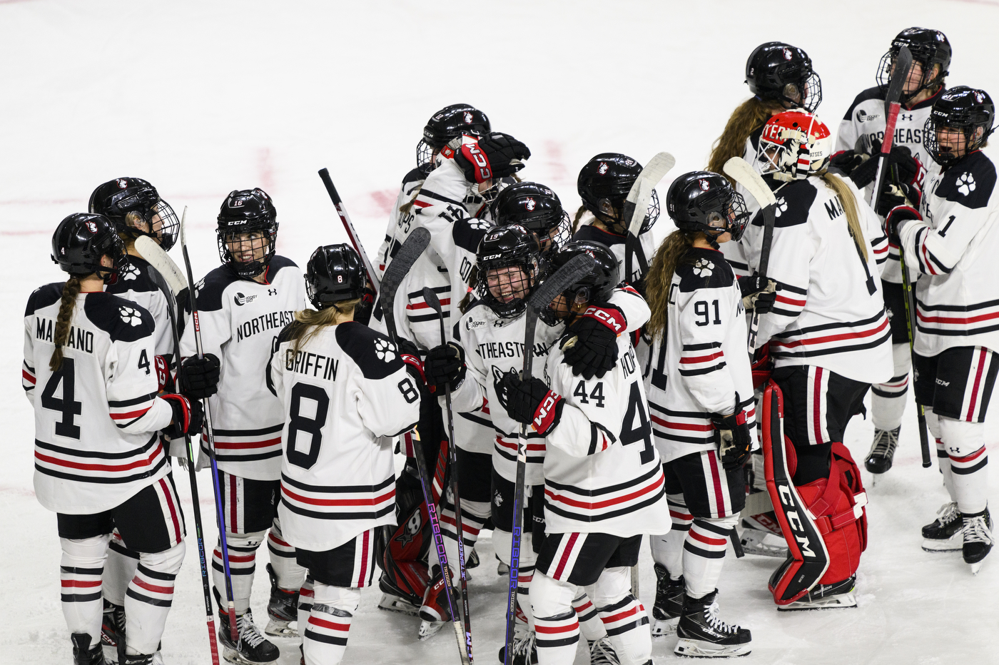 northeastern womens hockey team crowds together in celebration