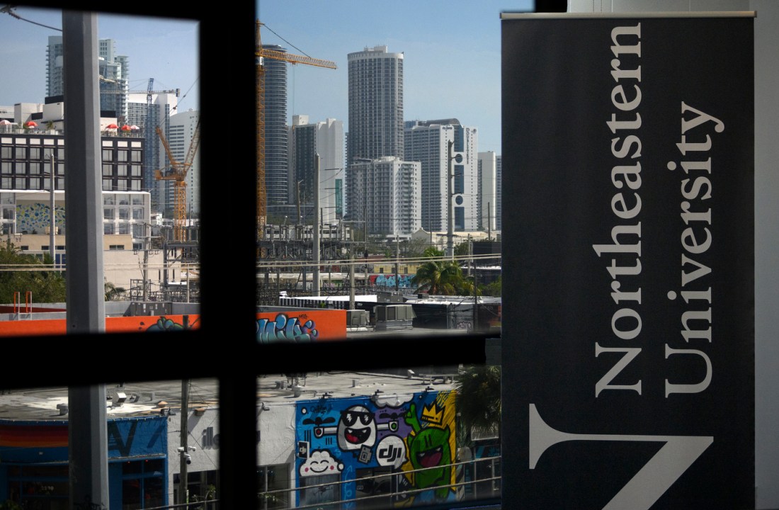 A partial view of the Miami skyline outside a window. A banner that says 'Northeastern University' is on the right