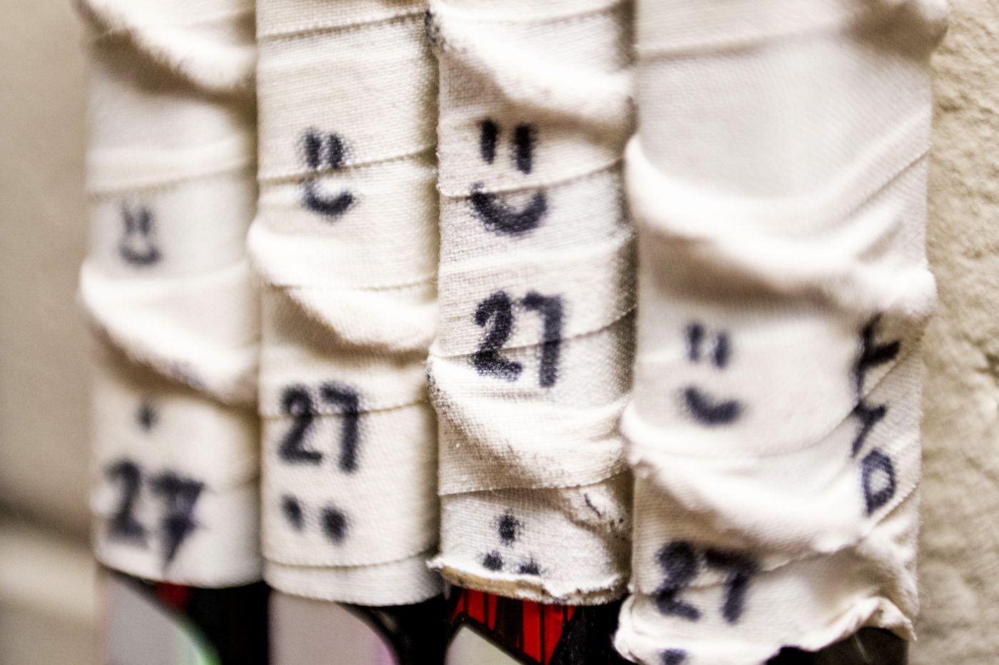 Happy faces and the number 27 are written in marker on the tape wrapped around 4 hockey sticks 