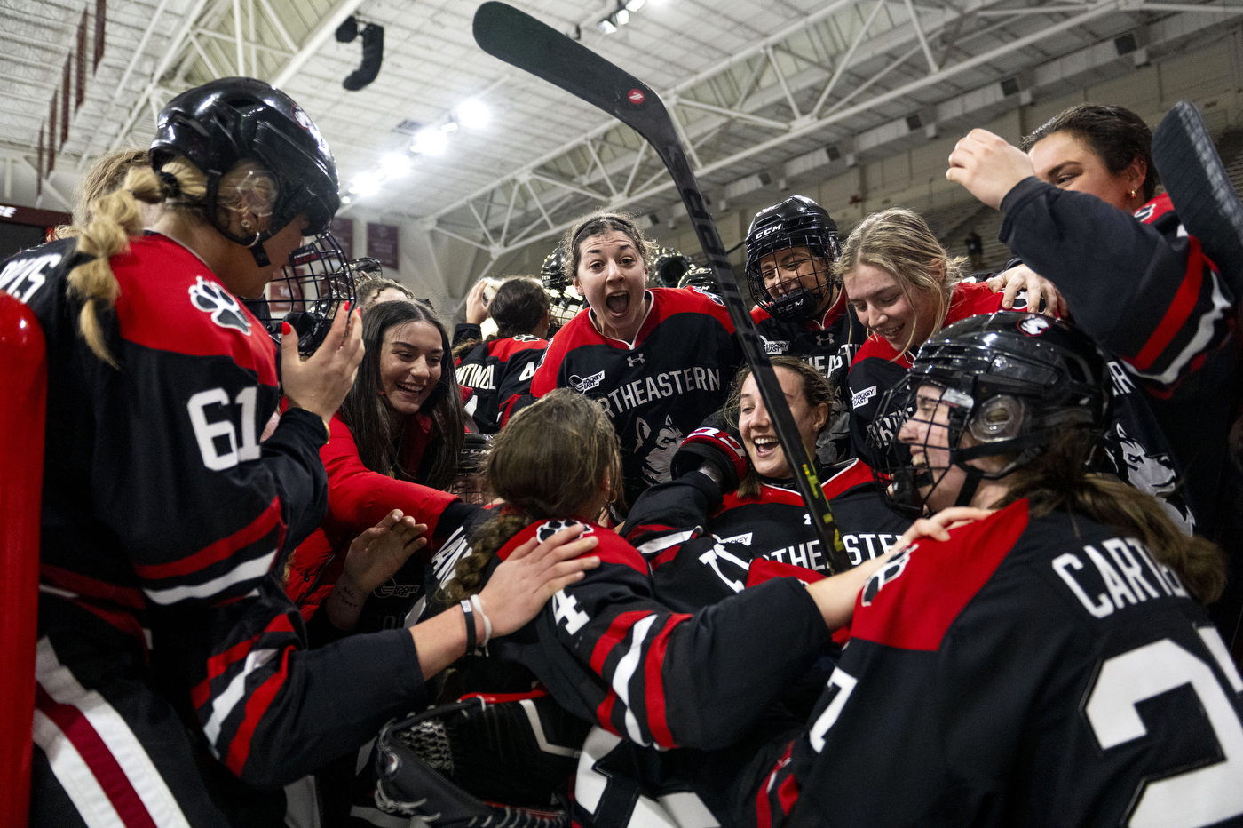 Members of the Northeastern women's hockey team huddle together in celebration