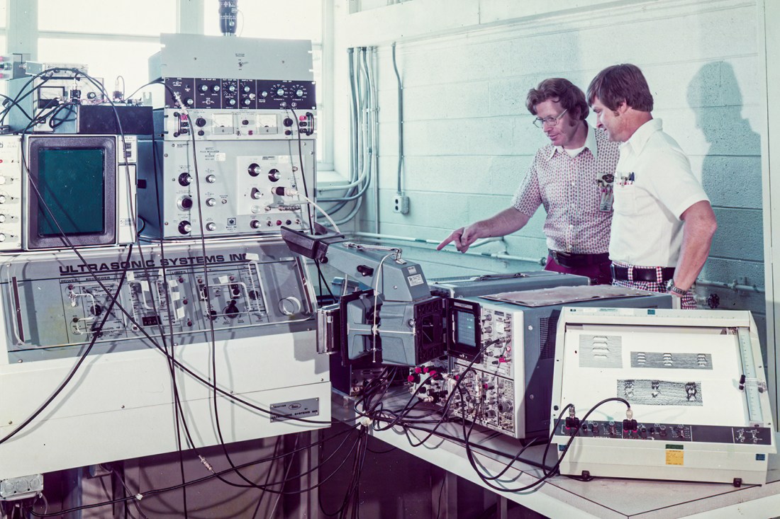 Heyman pointing at and explaining a sensor to a coworker
