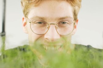 Oliver Homberg smiles behinds their growing microgreens