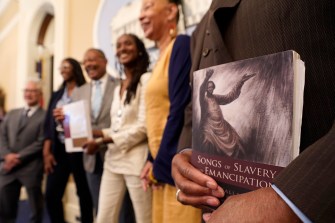 A person holds a copy of the book Songs of Slavery and Emancipation