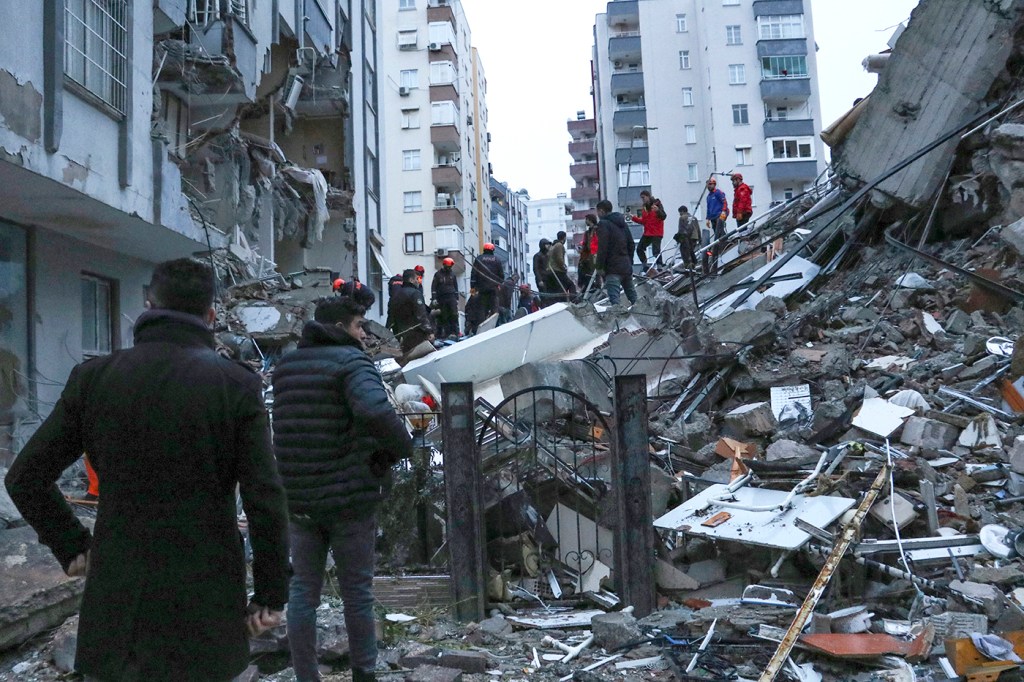 People examine the wreckage of a collapsed building in Turkey