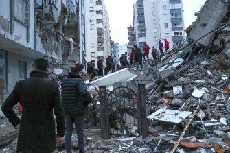 People examine the wreckage of a collapsed building in Turkey