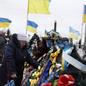 A crowd of people hold Ukrainian flags