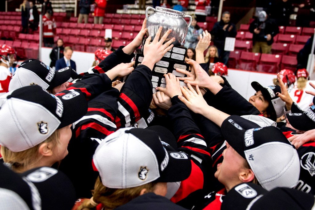 hockey players reaching for beanpot trophy