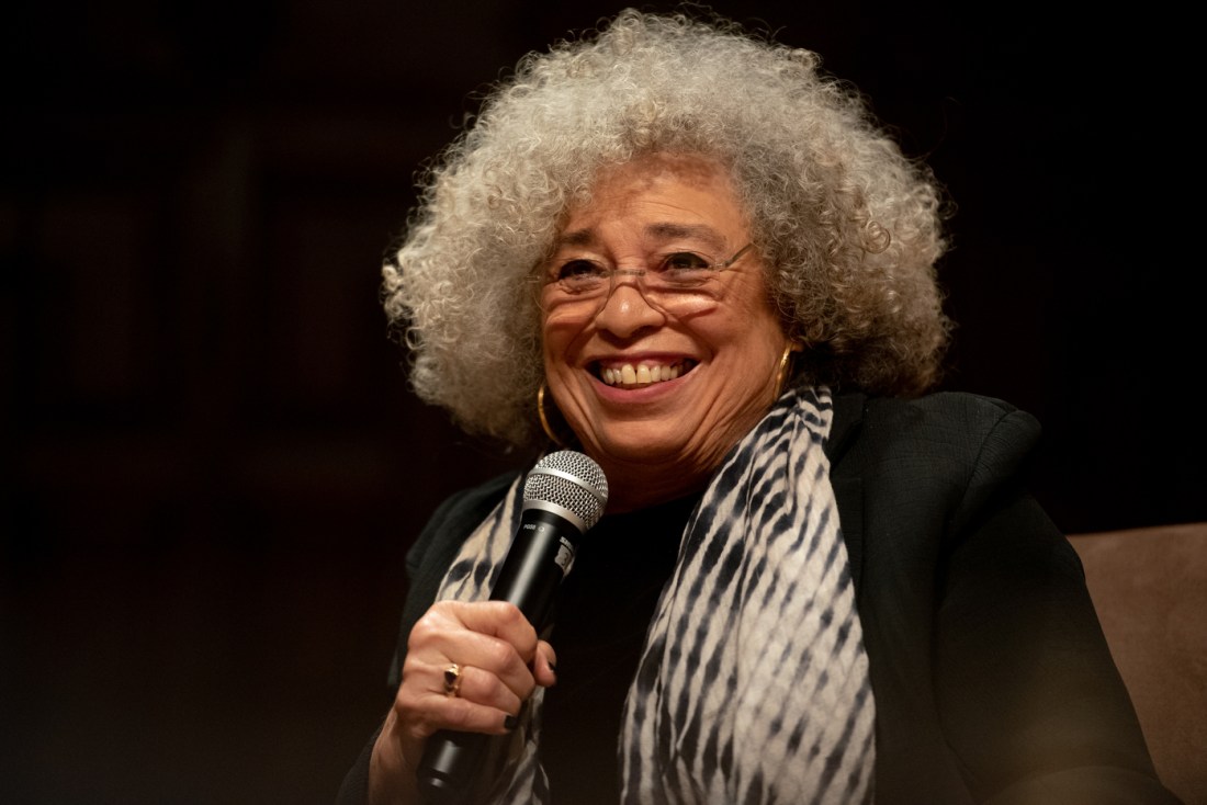 angela davis smiling while holding microphone