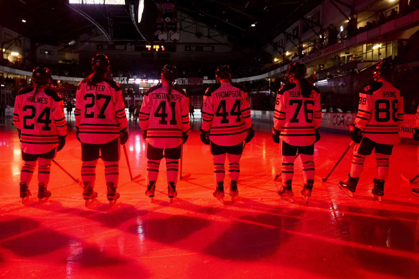 Hockey players stand on ice during pregame introductions