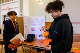 two boston public school students standing in front of their science fair project