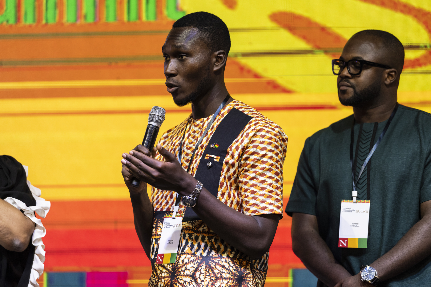 Kelvin Amakye speaking into microphone on stage at Global Leadership Summit in Ghana