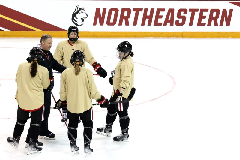 northeastern womens hockey players and coach on the ice