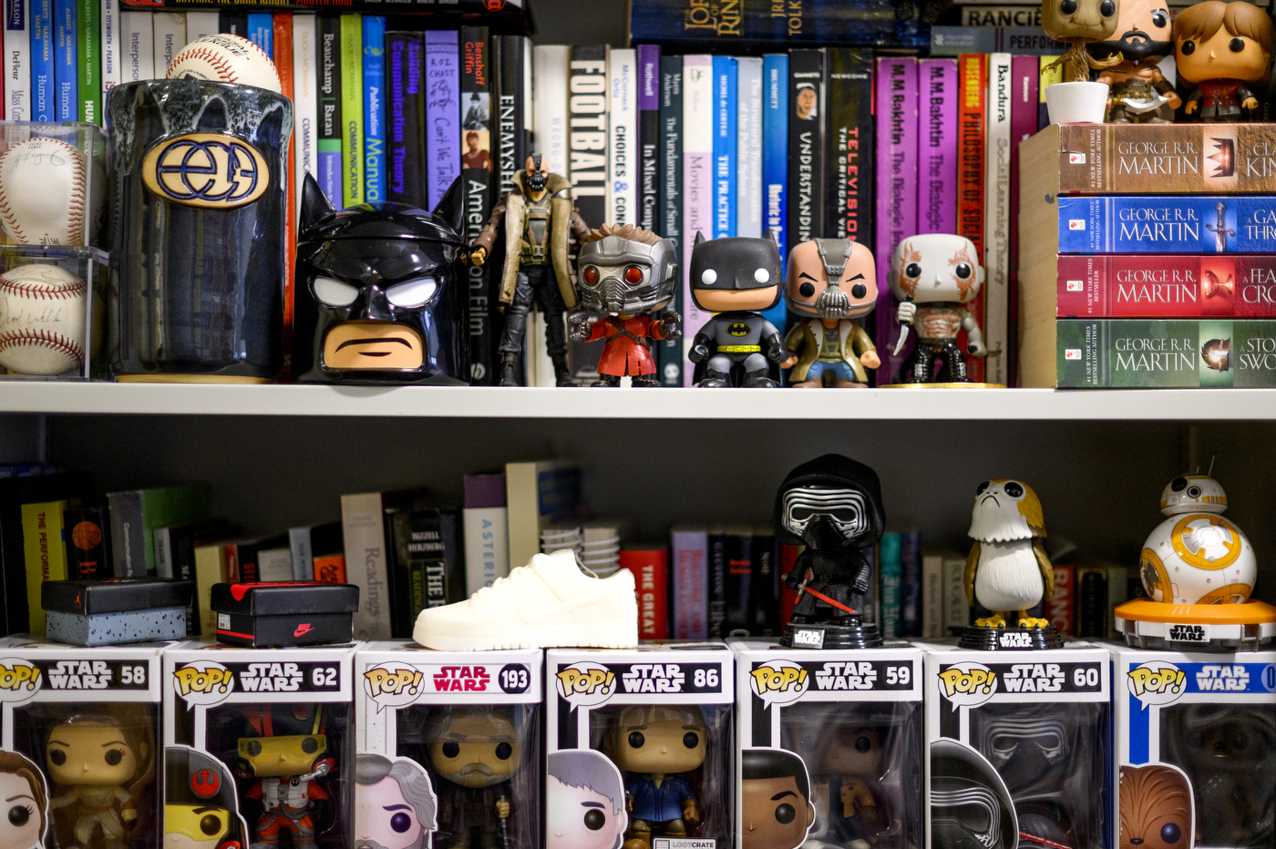 Superhero paraphernalia lines the shelves of a bookcase.