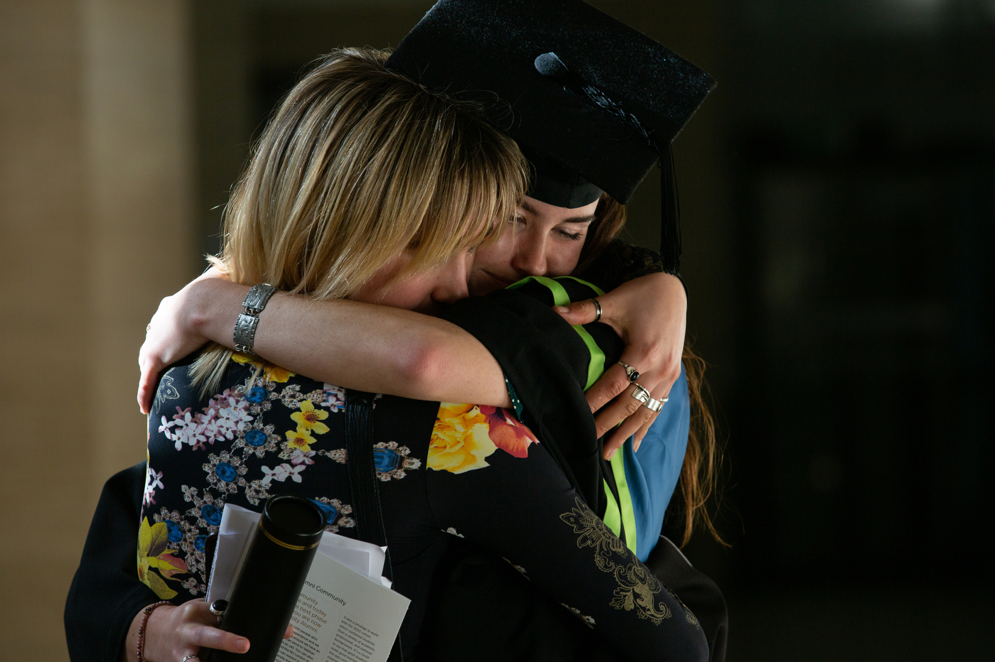 student hugging a guest at their graduation ceremony